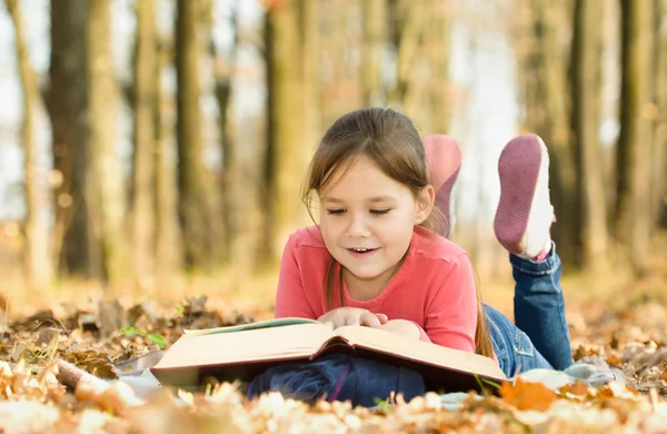 小さな女の子は屋外の本を読んでいます。 — ストック写真
