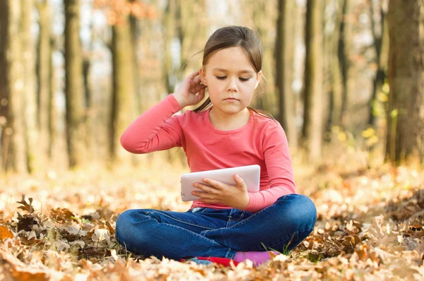 Little girl is reading a book outdoors — Stock Photo, Image