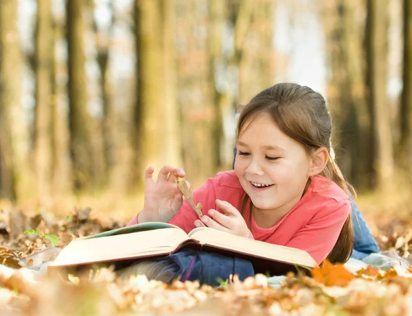 Little girl is reading a book outdoors — Stock Photo, Image