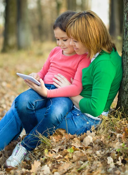 Mother is reading from tablet with her daughter — Stock Photo, Image