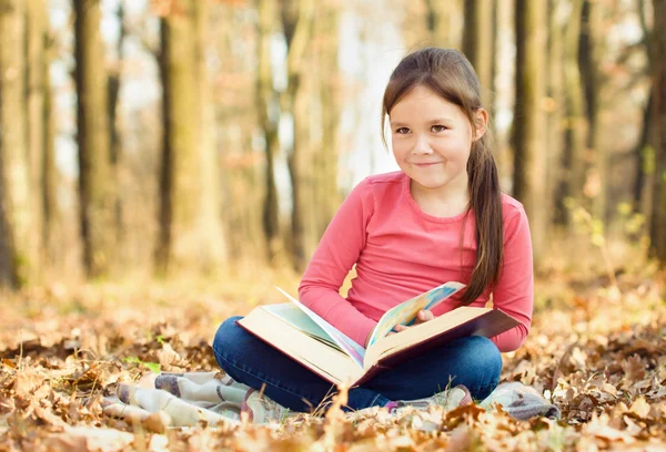 La bambina sta leggendo un libro all'aperto — Foto Stock