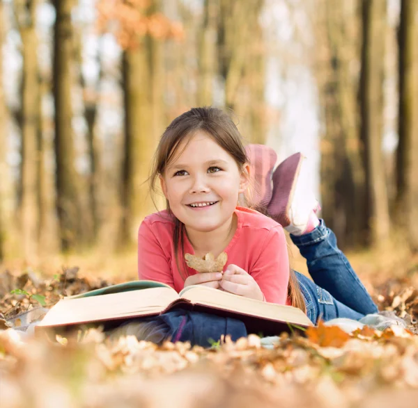 Маленькая девочка читает книгу на улице — стоковое фото