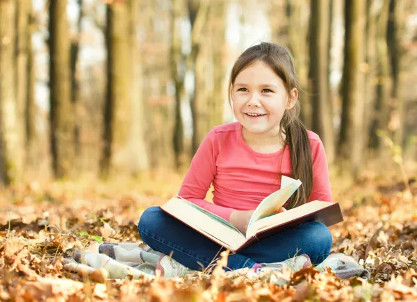 Küçük kız açık havada bir kitap okuma — Stok fotoğraf