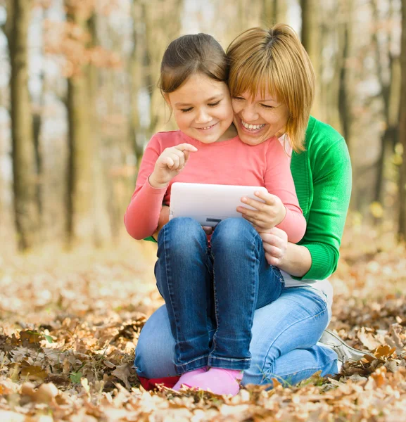 Mãe e sua filha está brincando com tablet — Fotografia de Stock