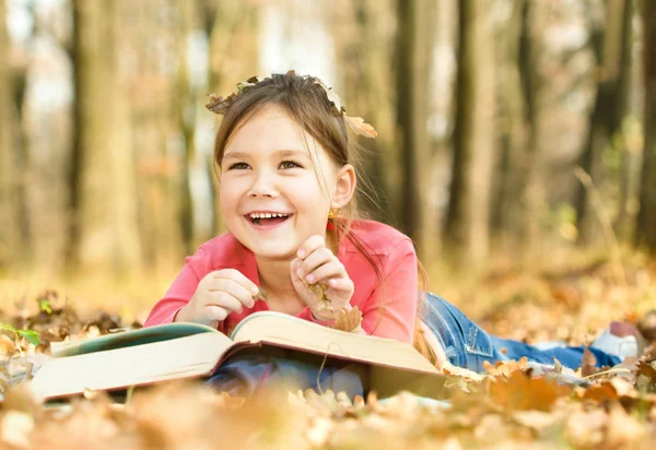 Little girl is reading a book outdoors — Stock Photo, Image