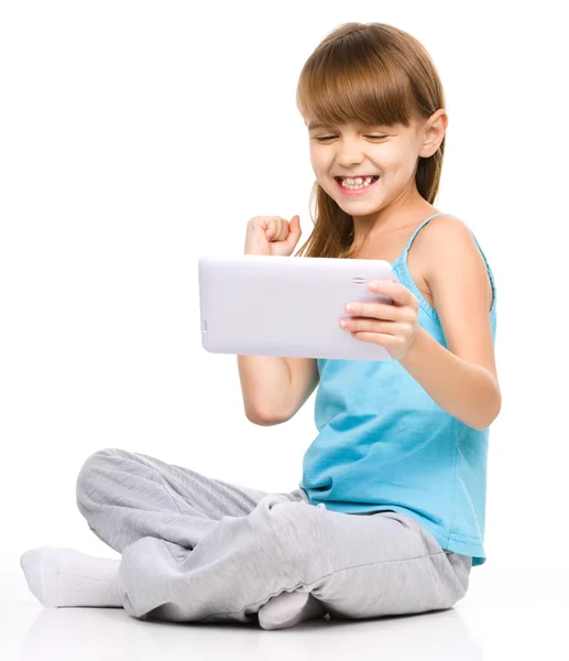Молодая девушка играет в игру с помощью планшета — стоковое фото