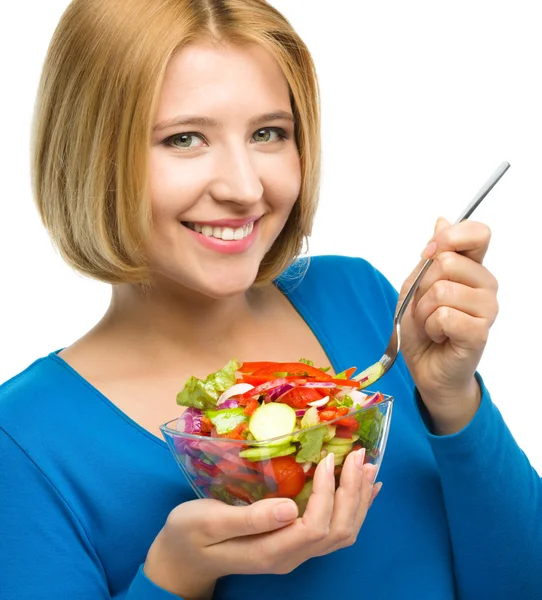 Jovem mulher atraente está comendo salada usando garfo — Fotografia de Stock