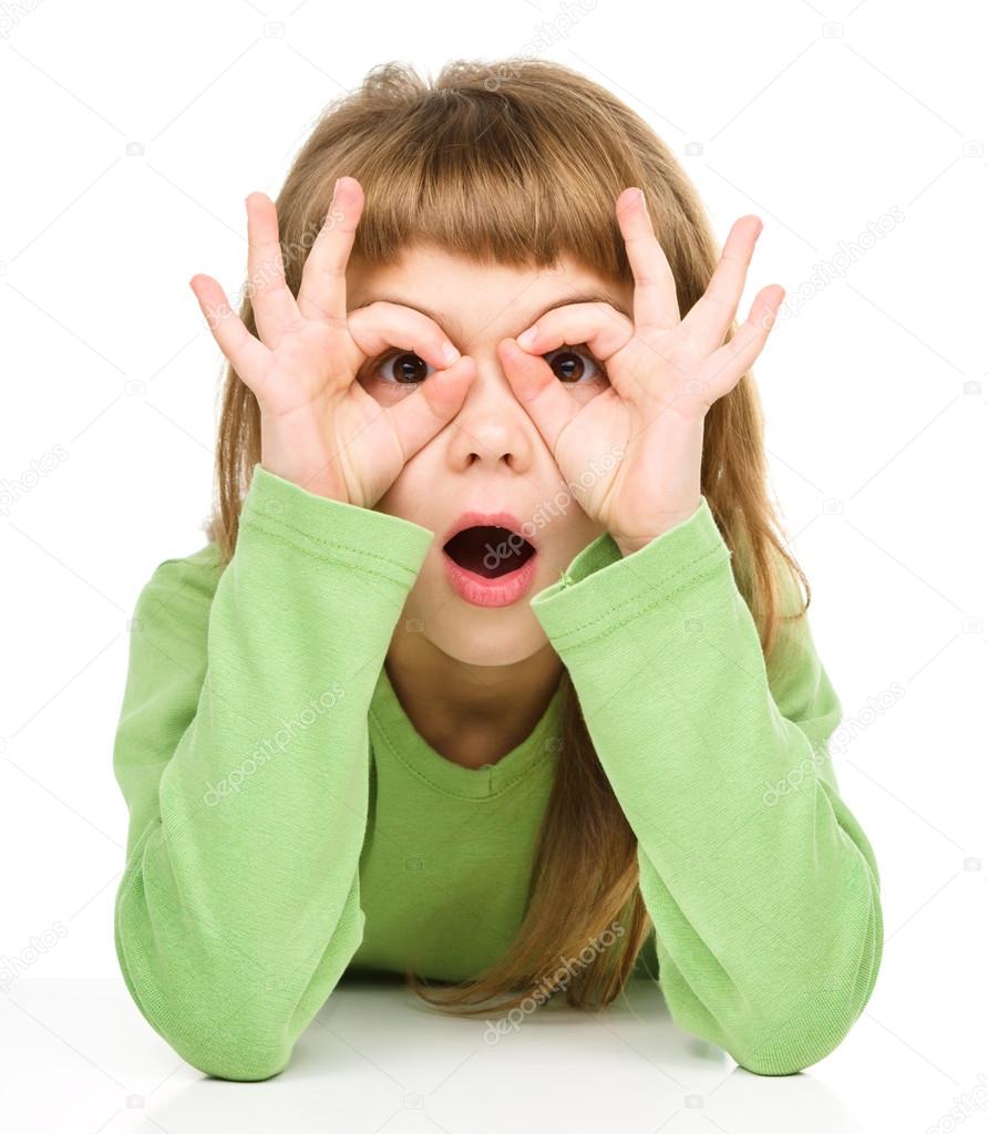 Astonished little girl is showing glasses gesture