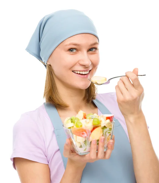 Jovem mulher atraente está comendo salada usando garfo — Fotografia de Stock