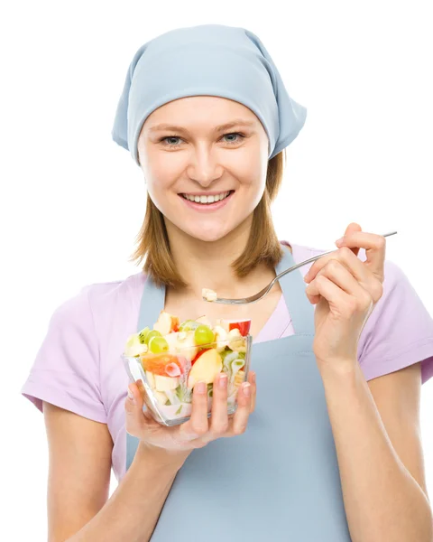 Jovem mulher atraente está comendo salada usando garfo — Fotografia de Stock