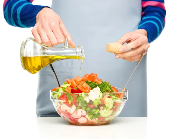 Koch gießt Olivenöl in Salat — Stockfoto