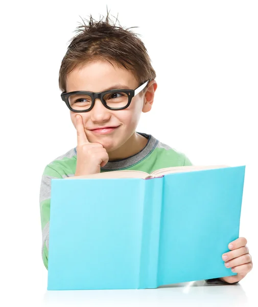 Niño joven está soñando despierto mientras lee libro — Foto de Stock