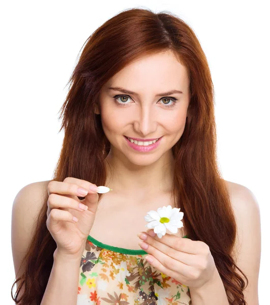 Jonge vrouw is scheuren van daisy bloemblaadjes — Stockfoto