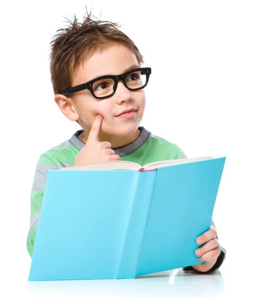 Jonge jongen is dagdromen tijdens het lezen van boek — Stockfoto