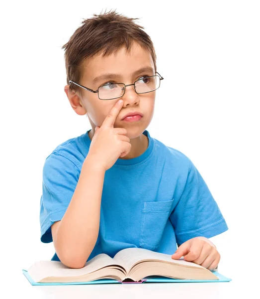 Niño joven está soñando despierto mientras lee libro — Foto de Stock