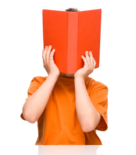 O rapazinho está escondido atrás de um livro. — Fotografia de Stock