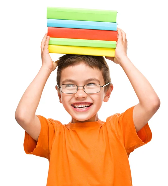 Le petit garçon tient une pile de livres — Photo