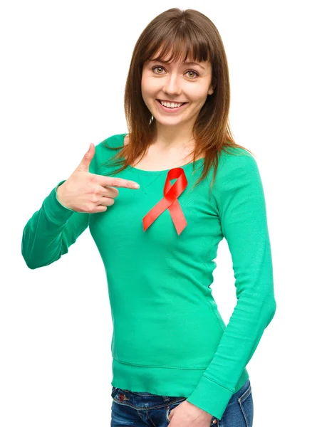 Woman is pointing to the red awareness ribbon — Stock Photo, Image