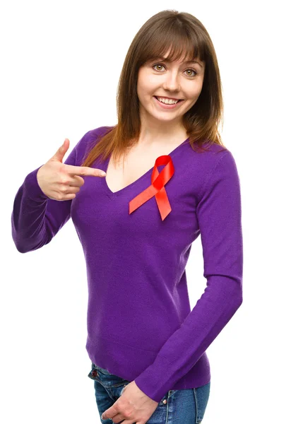 Woman is pointing to the red awareness ribbon — Stock Photo, Image