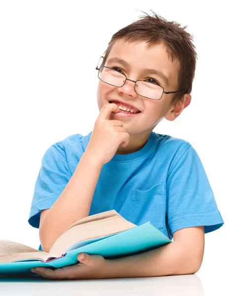Young boy is daydreaming while reading book — Stock Photo, Image