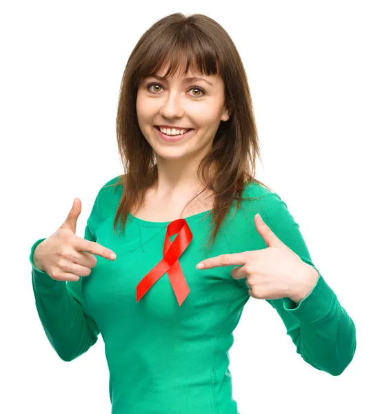 Woman is pointing to the red awareness ribbon — Stock Photo, Image