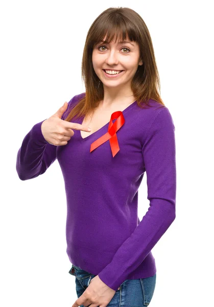 Woman is pointing to the red awareness ribbon — Stock Photo, Image