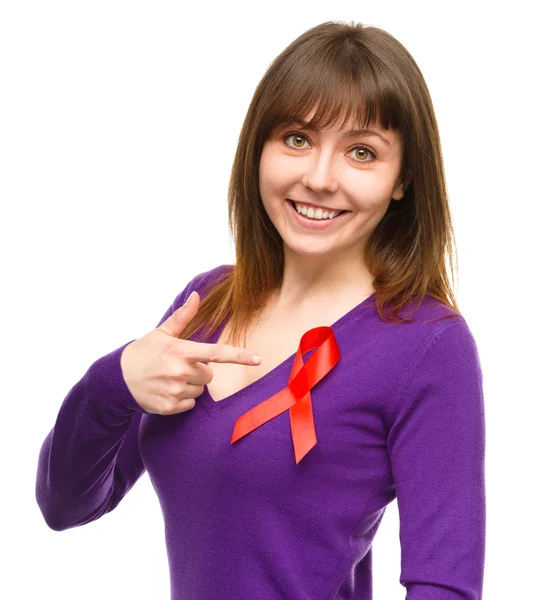 Woman is pointing to the red awareness ribbon — Stock Photo, Image
