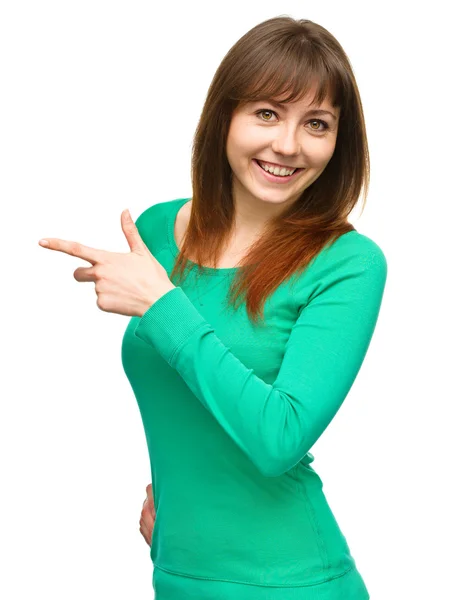 Portrait of a young woman pointing to the left — Stock Photo, Image