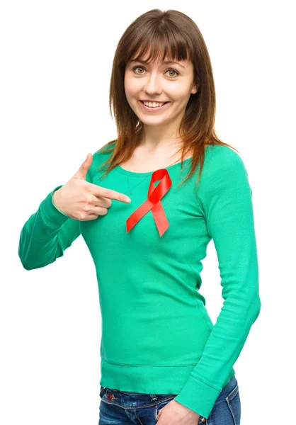 Woman is pointing to the red awareness ribbon — Stock Photo, Image