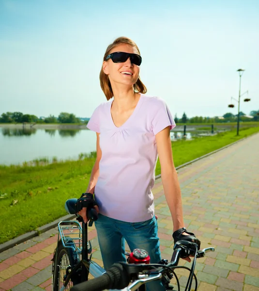 Giovane donna è in piedi dietro la bicicletta — Foto Stock