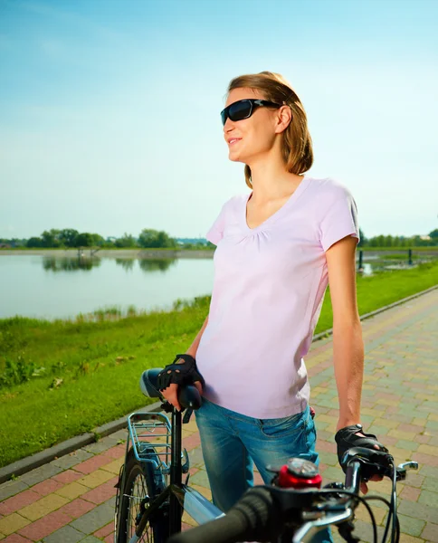 Giovane donna è in piedi dietro la bicicletta — Foto Stock