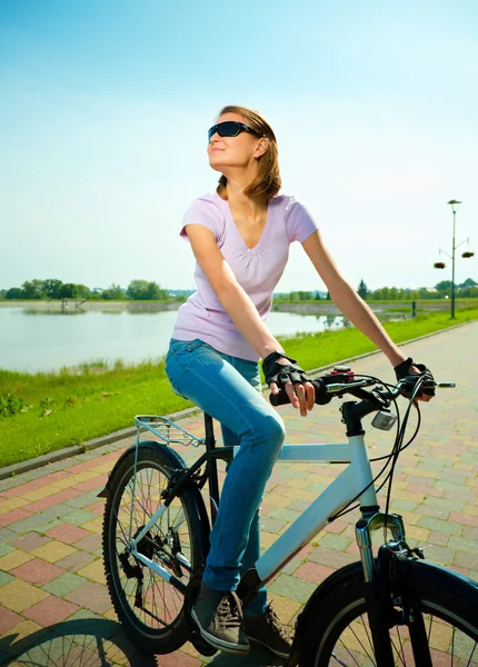 Mujer joven está sentada en su bicicleta — Foto de Stock