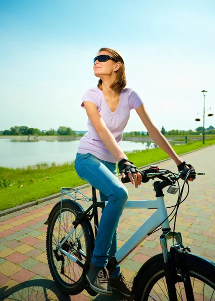 Jovem mulher está sentada em sua bicicleta — Fotografia de Stock