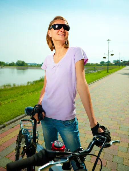 Молодая женщина стоит за велосипедом — стоковое фото