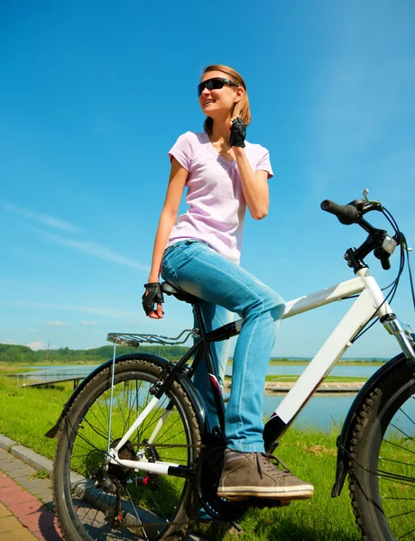 Mujer joven está sentada en su bicicleta — Foto de Stock