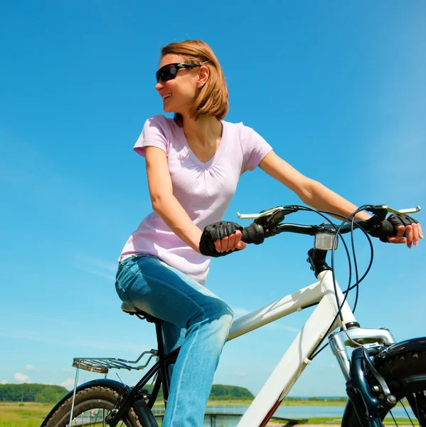 Mujer joven está sentada en su bicicleta — Foto de Stock