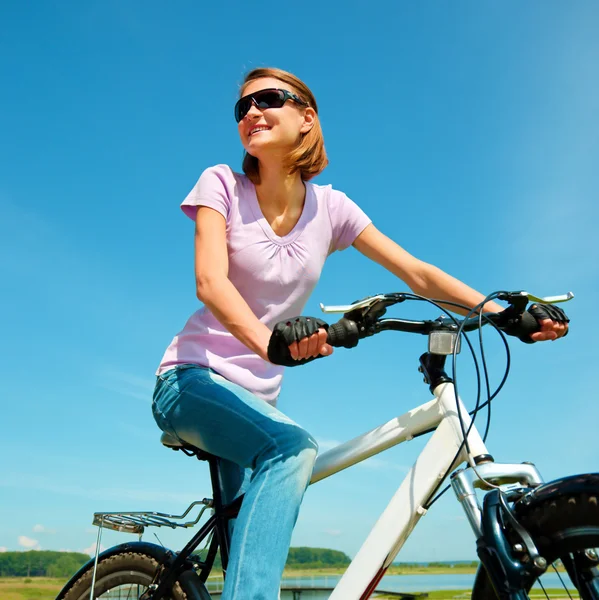 Jovem mulher está sentada em sua bicicleta — Fotografia de Stock