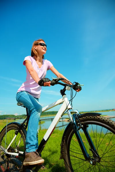 Mujer joven está sentada en su bicicleta — Foto de Stock