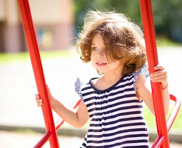 Joven chica feliz se balancea en el patio de recreo — Foto de Stock