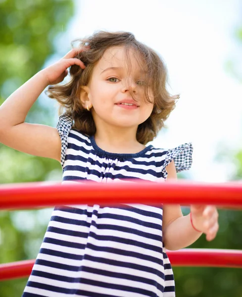 Menina bonito está jogando no parque infantil — Fotografia de Stock