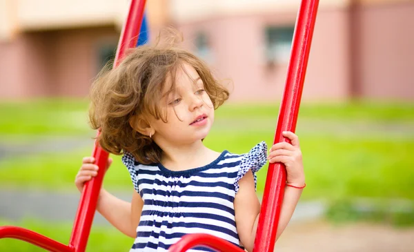 Молодая счастливая девушка качается на детской площадке — стоковое фото