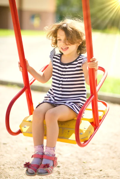 Jeune fille heureuse se balance dans l'aire de jeux — Photo