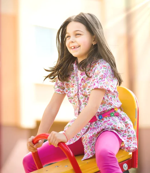 Молодая счастливая девушка качается на детской площадке — стоковое фото