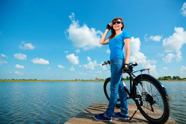 Jonge vrouw staat voor haar fiets — Stockfoto