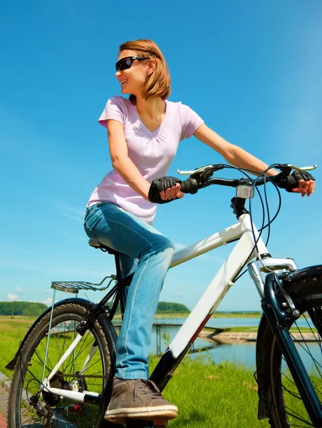 Mujer joven está sentada en su bicicleta — Foto de Stock