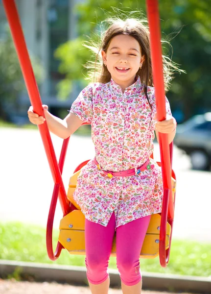 Jeune fille heureuse se balance dans l'aire de jeux — Photo
