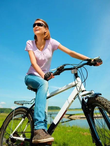 Jovem mulher está sentada em sua bicicleta — Fotografia de Stock