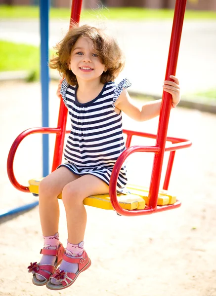 Joven chica feliz se balancea en el patio de recreo —  Fotos de Stock