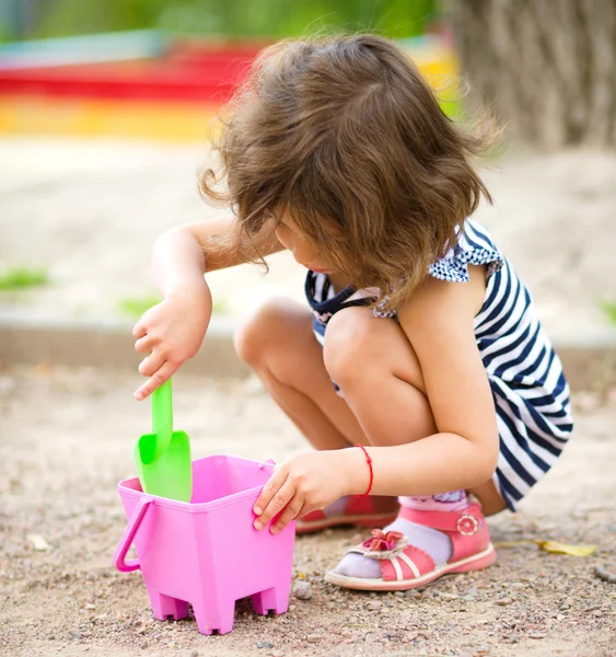 Liten flicka spelar med sand på lekplats — Stockfoto