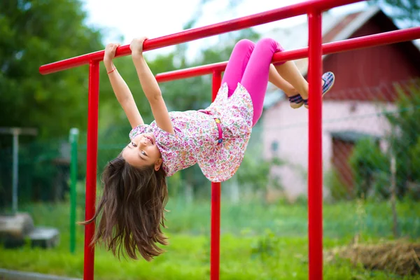 Menina bonito está jogando no parque infantil — Fotografia de Stock